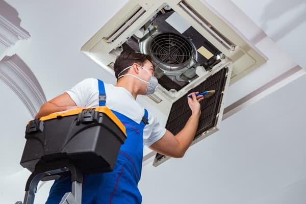 Worker repairing ceiling AC unit